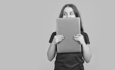 Sarı arka planda dizüstü bilgisayarın arkasında neşeli bir kız.