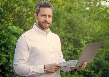 Neşeli iş adamının dışarıda online işi var. İş adamının bilgisayarında internet işi var. İş adamının fotoğrafının internette işi var. İş adamının internet işi var.