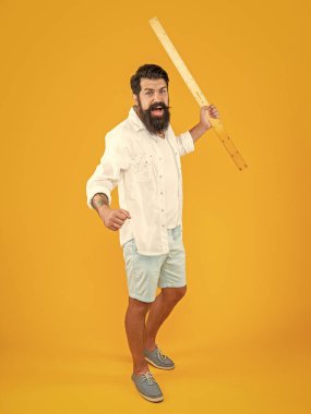 Cetveli kızgın adam sarıda izole edilmiş. Stüdyoda ölçücü cetveli olan adam. Arka planda cetveli olan adam. Ölçü cetvelli bir adamın fotoğrafı.