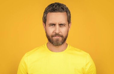 Sakallı adam arka planda sarı tişört giyiyor. Stüdyoda sarı tişört giyen bir adam. Sarı tişört giyen bir adamın fotoğrafı. Erkekler sarı tişört giyer..