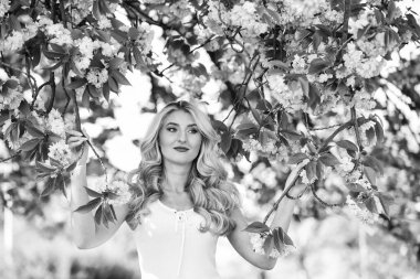 Bahar çiçeği açan ağaç. Mutlu bahar günleri. Kız bahçede sakura çiçeğinin tadını çıkarıyor. Kiraz ağacı. Çiçek aroması. Uyum ve kadın enerjisi. Bahar sembolü Çiçeklerin kadınları neden her zaman mutlu ettiğini..