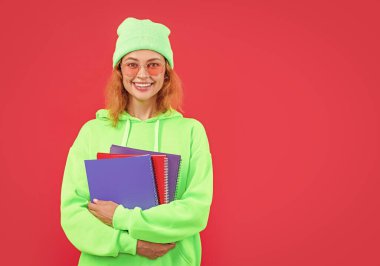 Stüdyoda fotokopi odası olan kız öğrenci. Öğrenci kızın elinde kitap tutarken çekilmiş bir fotoğrafı. Kız öğrencilerin okul eğitimi. Öğrenci kız öğrenci kırmızı arka planda izole.