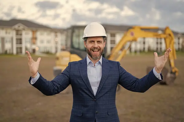 photo of glad successful construction business owner wearing hardhat. construction business owner in suit. construction business owner at site. construction business owner outdoor.
