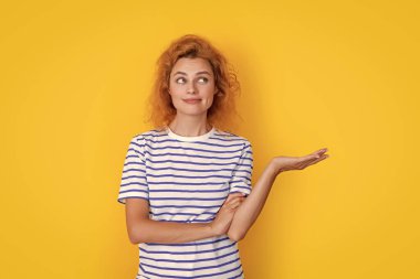 redhead woman portrait presenting product isolated on yellow background. portrait of young redhead woman in studio. adult redhead woman portrait.