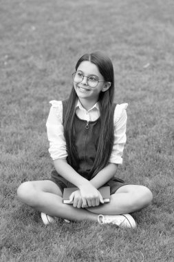 Happy teen school girl sitting legs crossed on grass. School and education. Back to school.