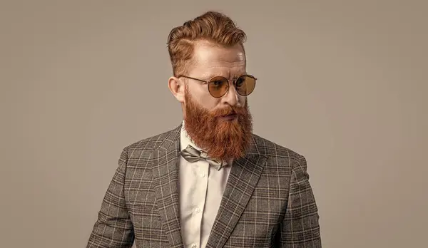 stock image handsome tuxedo formal man on background. photo of tuxedo formal man with beard. tuxedo formal man isolated on grey. tuxedo formal man in studio.