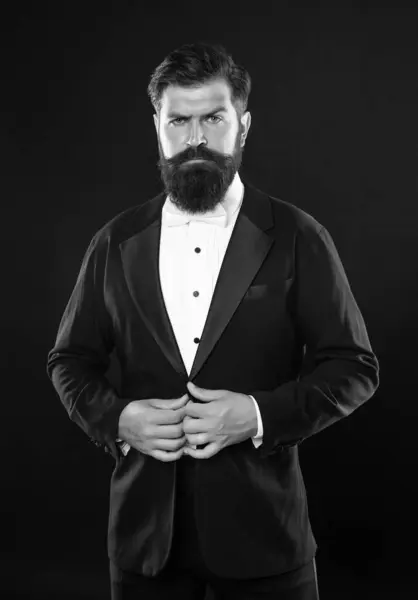 stock image brutal gentleman in tuxedo on black background, formalwear.