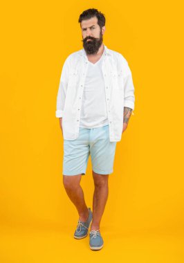 Sarıda izole edilmiş modaya uygun beyaz adam. Stüdyoda şık bir beyaz adam var. Arka planda şık bir beyaz adam. Beyaz adamın yaz modası giymiş şık bir fotoğrafı..