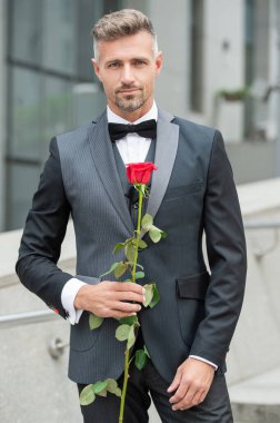 Siyah smokinli zarif bir adam. Smokin papyon takan adam dışarıda. Kırmızı güllü, olgun smokinli adam..