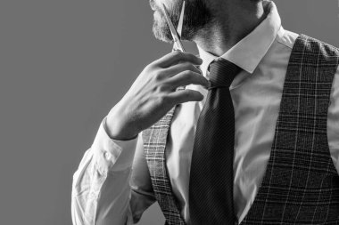 Kuaförde berberlik yapan adam, fotokopi odası. Sakallı adam kuaförü. Gri arka planda izole edilmiş makaslı traşsız adam kuaförü. Adam kuaför makasıyla saç kesiyor..