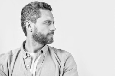 Sakallı sakallı adamın fotoğrafı yana baksın. Sakallı, sıradan tişörtlü bir adam. Gri arka planda sakallı bir adam. Stüdyoda sakallı bir adam..