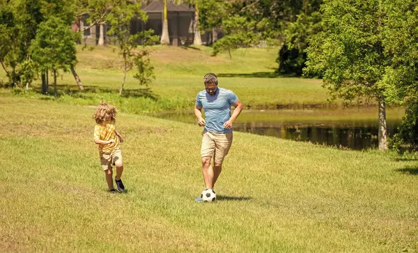 Father dad and son enjoying outdoor activities together. Outdoor adventures between father and son. Active father son playing football in summer. Father and child son teaming up outdoor. weekend.