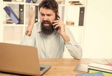 Stresli iş adamı cep telefonuyla bağırıyor, laptopla çalışıyor, stres altında..