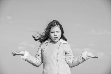 Gökyüzü arka planında ürünü sunan kafası karışmış bir çocuk.