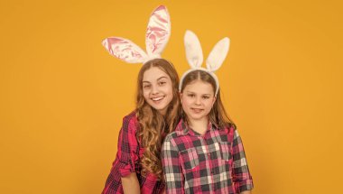 Sarı arka planda tavşan kulaklı mutlu Paskalya çocukları.