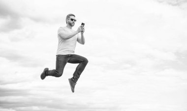 Adam zıplıyor ve arka planda akıllı telefondan sohbet ediyor. Boşluğu kopyala.