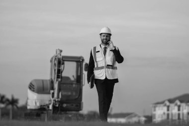 Mimar işgali adamı dışarıda telefonla konuşuyor. Mimar işgali mühendisi kask takıyor. Mimarlık mesleğinin fotoğrafı. Mimar işgali adamı..
