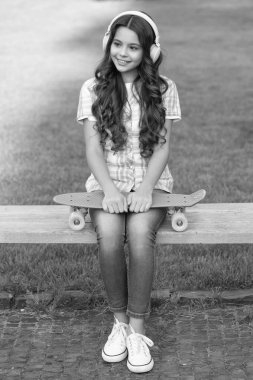 happy teen girl with skateboard outdoor. teen girl with skateboard in headphones. teen girl with skateboard outside. photo of teen girl with skateboard listen music. clipart