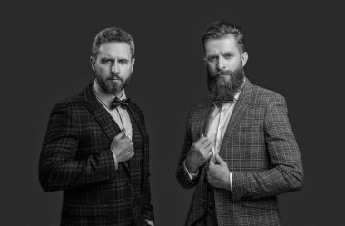 Smokinli yakışıklı beyefendiler stüdyoda. Smokinli resmi beyefendiler arka planda. Smokin giymiş resmi beyefendilerin fotoğrafı. smokinli resmi beyefendiler kırmızı üzerine izole edilmiş..