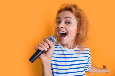 Sarı arka planda izole edilmiş mutlu karaoke kadın şarkıcı. Genç şarkıcı kadın karaoke stüdyosunda şarkı söylüyor. Kadın karaoke şarkıcısı ve mikrofon..