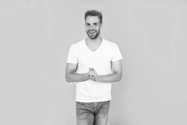 Saç ve sakal bakımı. Kendine güvenen ve yakışıklı, tıraşsız adam. Erkek modası. Erkek güzelliği. Beyaz gömlekli kıllı adam. Sarı arka planda sakallı neşeli genç adam..