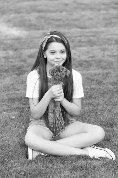 stock image cheerful girl sitting on grass with spring flowers.