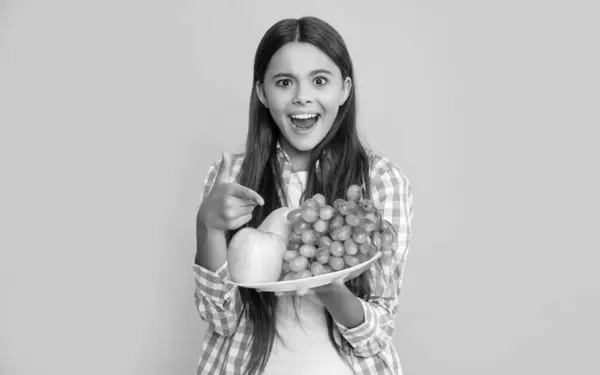 stock image surprised child with fruit plate on yellow background.