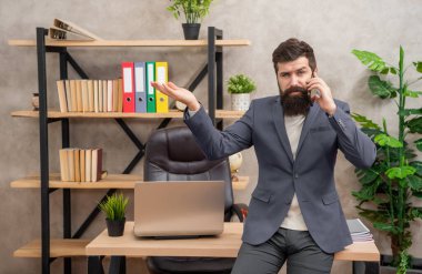 Ciddi profesyonel bir adam cep telefonuyla konuşuyor. Ofis fotokopi odasında reklam jesti gösteriyor. Ürün sunuyor..