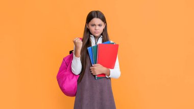 Okul çantalı öfkeli çocuk ve sarı arkaplan üzerine çalışma kitabı.