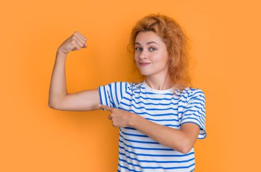 Kızıl saçlı kadın sarı arka planda izole edilmiş trisepsler gösteriyor. Stüdyodaki genç kızıl saçlı kadının portresi. Yetişkin kızıl kadın portresi.