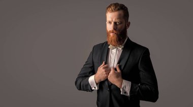 Smokinli beyefendi stüdyosu, fotokopi odası. Zarif smokin giyen bir beyefendi. Smokin modası. Smokinli yakışıklı sakallı beyefendi gri arka planda izole edilmiş..