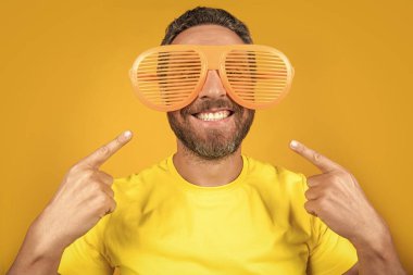 Parti adamı stüdyoda eğlenceli bir işaret parmağıyla gülümsüyor. Parti adamının fotoğrafı gözlüklü yaz eğlencesine çıkar. Parti adamı yaz eğlencesini sarıda yalnız geçirir. Parti adamı yaz eğlencesini arka planda yapar..