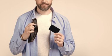 Ödeme kartı ve cüzdanı olan bir adam stüdyo arka planında izole edilmiş, kırpık manzaralı. Stüdyoda ödeme kartı ve cüzdanı olan bir adam. Ödeme kartı ve cüzdanı olan bir adam. Ödeme kartı olan bir adamın fotoğrafı..