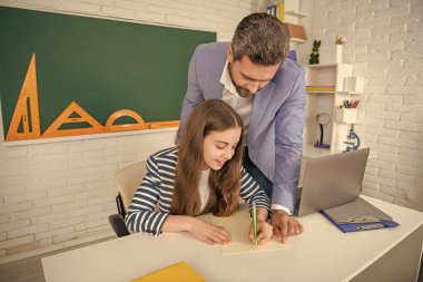 Sınıfta hocası olan neşeli çocuk dizüstü bilgisayar kullanıyor..