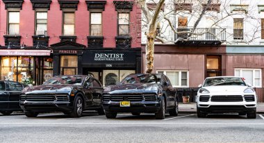 New York, ABD - 15 Mart 2024: Porsche Cayenne Sokağa park edilmiş iki araba, ön manzara.