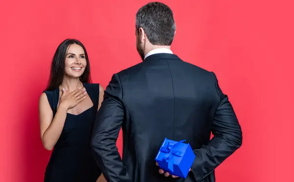 Romantic proposal with gift. Present. Man making proposal to woman. Man give present gift box for Valentines day to woman. Happy Valentines day. Couple in love isolated on red. Couple offering.