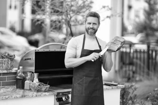 happy man with grill salmon. man cook salmon on grill. chef man cooking salmon on grill outdoor. grill salmon fish at man wear apron.