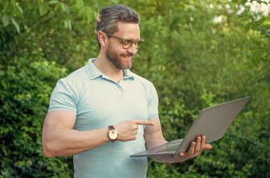 Programcı açık havada, işaret parmağıyla. Bilgisayarda çalışan programcı. Bilgisayarda programcının fotoğrafı. Programcı çevrimiçi.