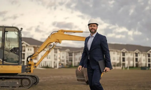 businessman inspecting building plan outdoor, copy space. photo of businessman with building plan wearing hardhat. businessman with building plan. businessman check building plan at site.