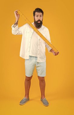 Şok olmuş bir adam okulun hükümdarı sarıda izole edilmiş. Stüdyoda okul yöneticisi var. Arka planda okulun yöneticisi var. Man Hold okul hükümdarının fotoğrafı..