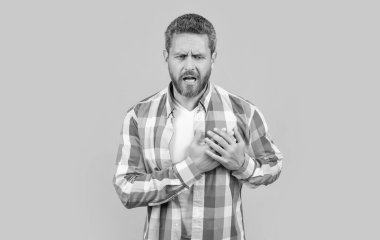 Adam stüdyoda kalp kırıklığından muzdarip. Beyaz gömlekli bir adamın kalp ağrısı. Kalp ağrısı çeken bir adam. Beyaz adam kalp ağrısı çekiyor. Sarı arka planda izole edilmiş..