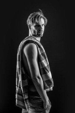 Stüdyo arka planında kaslı kaslı bir adam. Kaslı adam karın kaslarına havlu takıyor. Kaslı bir adamın fotoğrafı. Siyah arka planda izole edilmiş karın kaslarında havlusu olan kaslı adam..