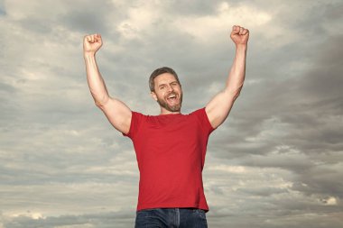 Happy man making winning gesture sky background. winning guy celebrating victory keeping arms raised. Winning.