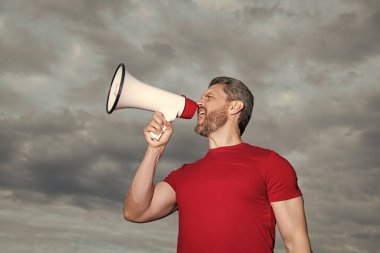 man in red shirt speak in loudspeaker on sky background.