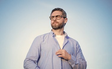 pensive bearded man standing peaceful. pensive man in glasses outdoor. pensive man on sky background.
