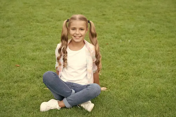 stock image summer relax in park. teen girl sitting outdoor. childhood lifestyle of teen. relax on summer lawn. girl relax peacefully on the grass. happy childhood of teen girl. copy space advertisement.