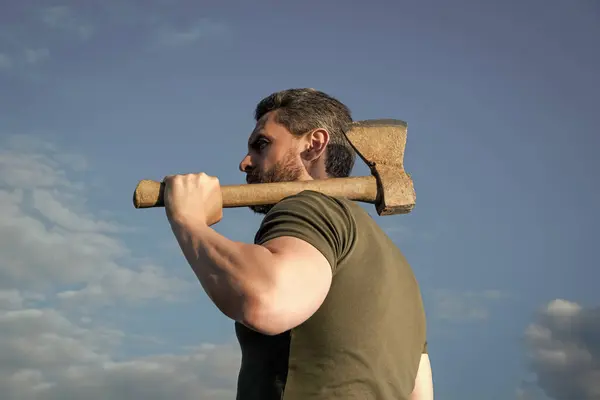 stock image back view of man with axe. woodman man hold ax. brutal man on sky background.