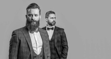 Smokin giyen beyler, gri arka planda izole edilmiş, fotokopi alanı ve seçici bir odak noktası var. Smokinli iki beyefendi. Smokin giyen beyefendilerin stüdyo fotoğrafı. Resmi smokin giymiş zarif beyefendiler..