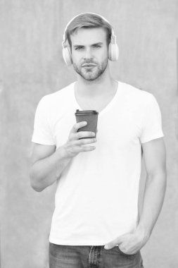 Adam açık havada kahve eşliğinde müzik dinliyor. Dışarıda müzik dinleyen bir adam. Müzik dinleyen ve gömlek giyen bir adam. Kulaklıkla müzik dinleyen bir adamın fotoğrafı..