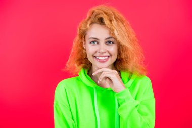 Moda kıyafetleri ve tarzı. Kazaklı beyaz bir kadın. Sıradan bir yaşam tarzı. Havalı kapüşonlu giyen kızıl saçlı kız. Pembe üzerine izole edilmiş şık bir kadın. Hareketli moda kız kapüşonlu giyer. Moda simgesi.